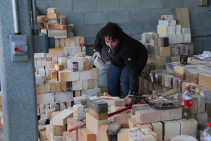 Tamara Franks, fine arts and psychology senior, gathers up bricks to hand to her fellow classmates during the construction of the kiln.