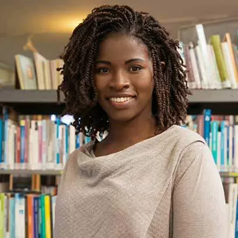 A woman smiling for a portrait in front of a bookshelf.