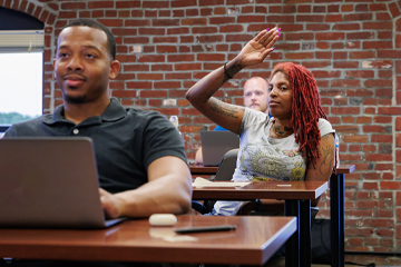 A group of graduate students at their desks in a classroom.