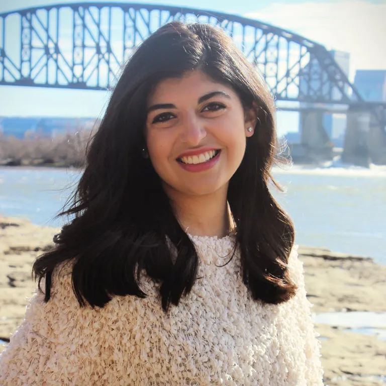 IU Southeast Honors Program student Keziah Jones posing in front of a bridge over the Ohio River and smiling