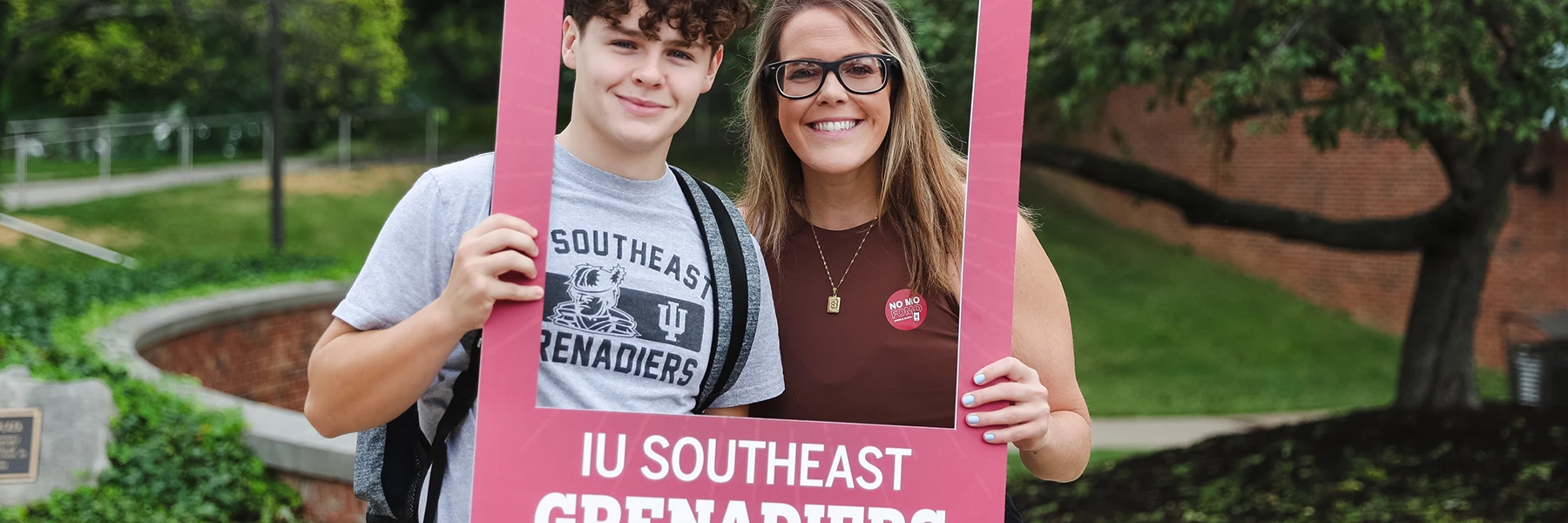 Two students holding up an IU Southeast photo frame and smiling