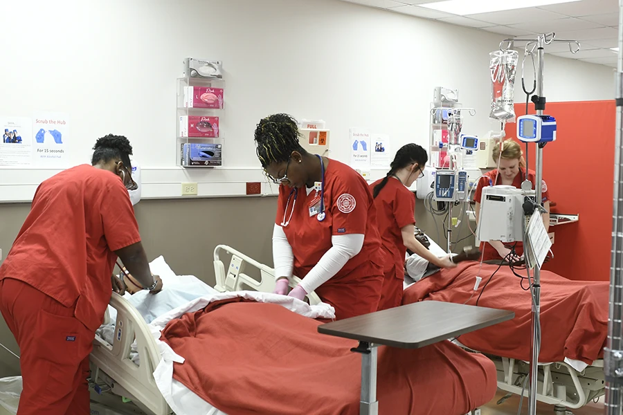 IU Southeast nursing professor recording two students treating a patient in a lab