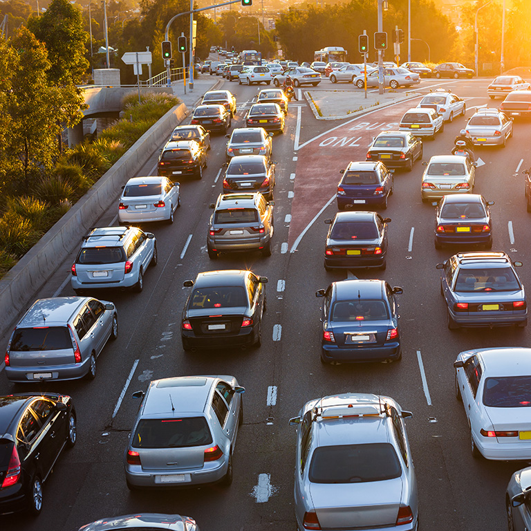 Four lanes of cars in city traffic at sunset