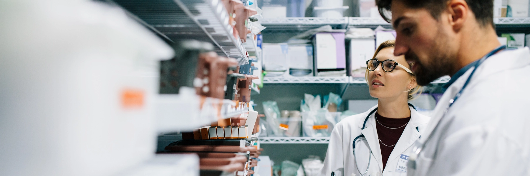 Two pharmacists checking medicine inventory at hospital pharmacy. 