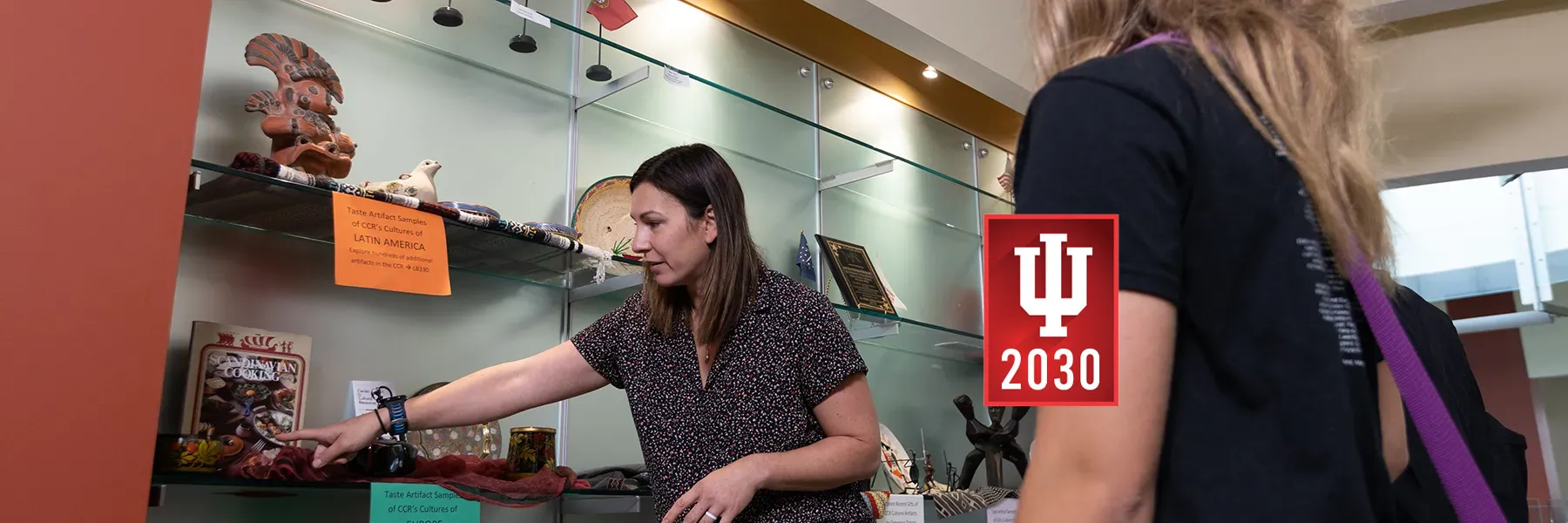 IU Southeast librarian pointing at cultural artifact shelf