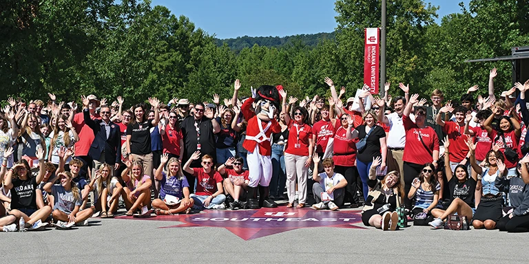 Large group of students and faculty and the Grenadier mascot waving outside on IU Southeast's campus