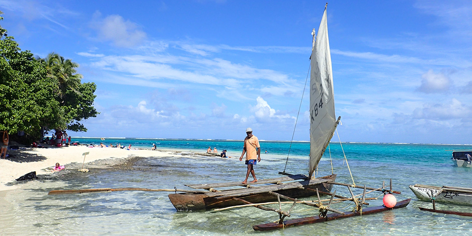 Man walking by the ocean next to a boat