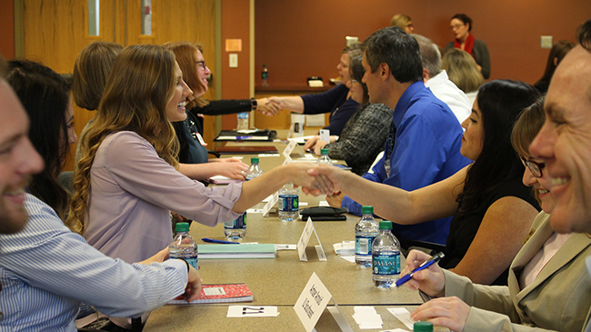 Students and local business leaders speak and shake hands.