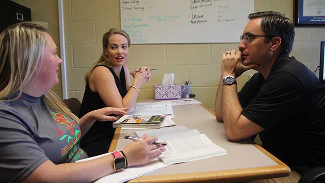 MBA students Ashley Blackerby and Megan Pfeifer brainstorm with John Ross during a preparatory meeting for an online class they will co-teach.