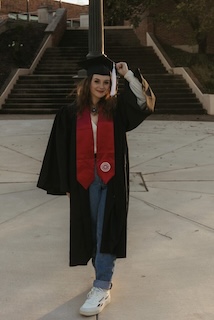 Alizae Clayton stands in McCullough Plaza on the IU Southeast campus in her graduation regalia.