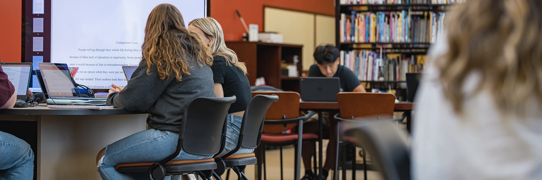 Students in the IU Southeast Writing Center sitting at tables and working on laptops
